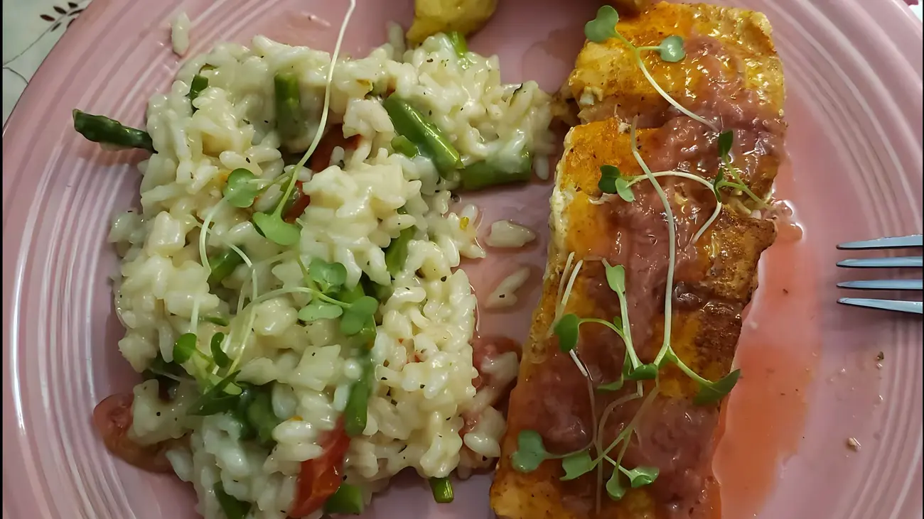 A plate featuring pineapple glazed salmon, asparagus risotto, and grilled pineapple, showcasing a colorful array of rice and vegetables